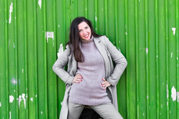 Chica sobre un fondo verde. Con un abrigo gris cálido. Retrato de la hermosa niña sobre un fondo verde — Foto de Stock