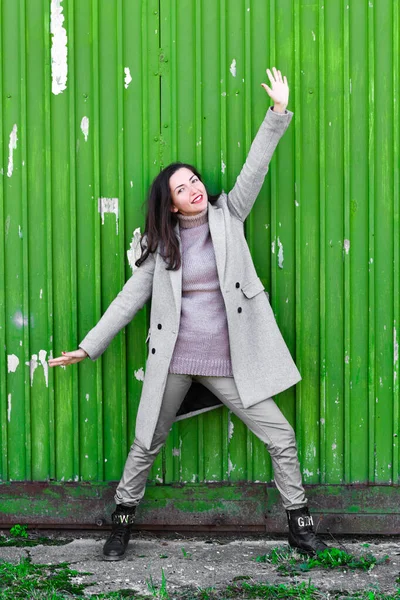 Meisje op een groene achtergrond. In een warme grijze jas. Portret van het mooie meisje op een groene achtergrond — Stockfoto