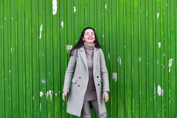 Portret van jonge vrouw tegen een groene achtergrond. Draag een hoed en jas. plaats om op te nemen. gekleed in een koude pagode. kleren en stijl. natuurlijke emoties. Portret van jonge vrouw tegen een groene backgro — Stockfoto