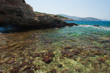 Taşlarla dolu bir sahil. Su taşları yarıp geçiyor.