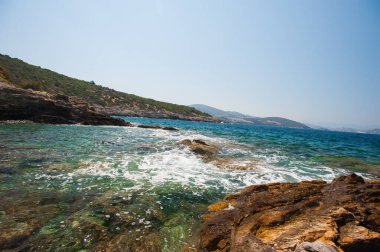Taşlarla dolu bir sahil. Su taşları yarıp geçiyor.