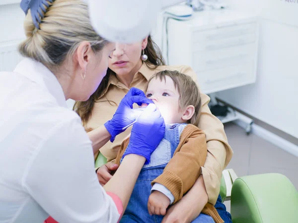 Dişçi randevusundaki bir çocuk. Annelerimin dizlerinin üstünde oturuyorum. Çocuğun ve annenin doktorunu ziyaret et. çocuk 0-1 yaşında. 