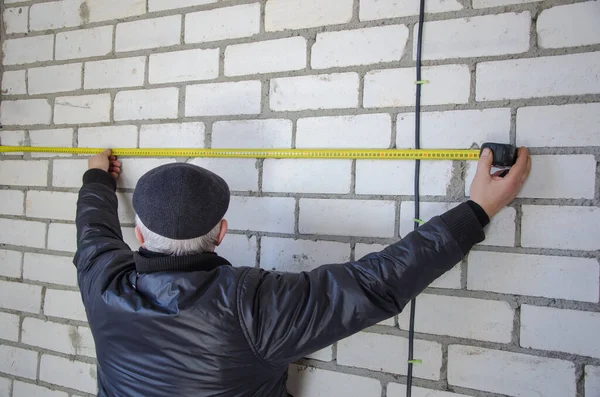Un hombre mide el cableado, la precisión es importante — Foto de Stock