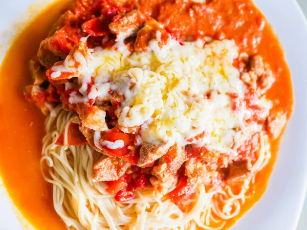 pasta with meat and tomatoes on a white plate