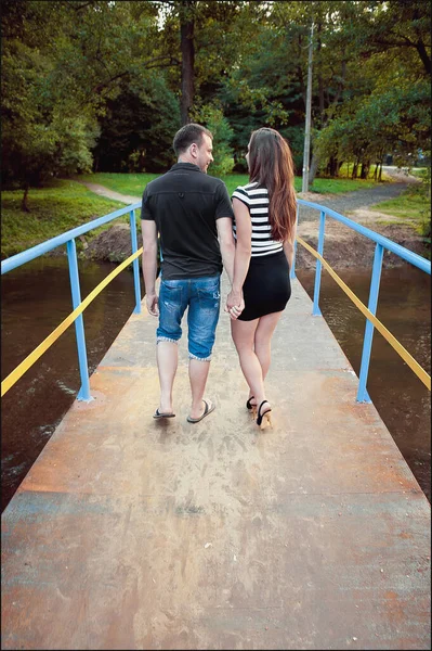 Verliebtes Paar läuft über Brücke in Richtung Wald — Stockfoto
