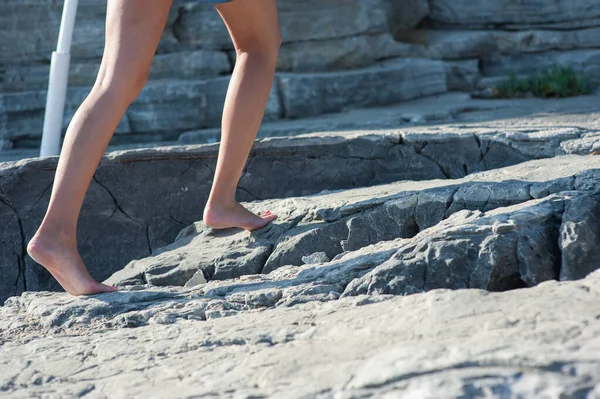 A menina vai descalça sobre as rochas, subindo — Fotografia de Stock