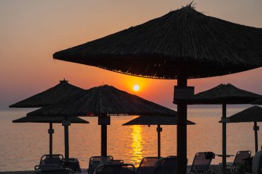 Gün batımında deniz kenarında plaj şemsiyeleri.