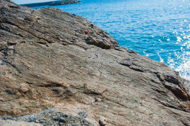 Güneşli havada deniz kenarında büyük düz bir taş.
