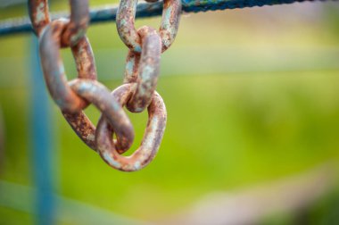 Paslı zincir, öğleden sonra mavi bir çite asılır.