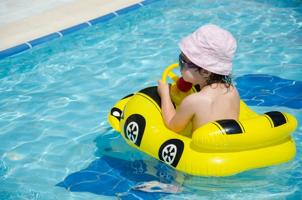 Boy on an inflatable yellow car in the pool — Stock Photo, Image