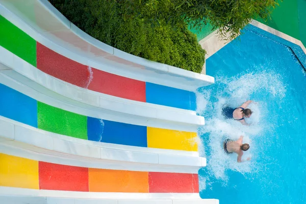 Pareja hombre y mujer paseo con toboganes de agua de colores. actividades familiares —  Fotos de Stock