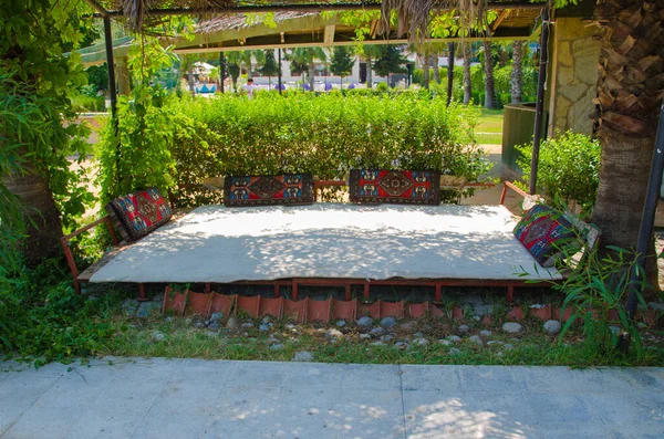 Cama en la calle con almohadas de colores cerca de los arbustos — Foto de Stock