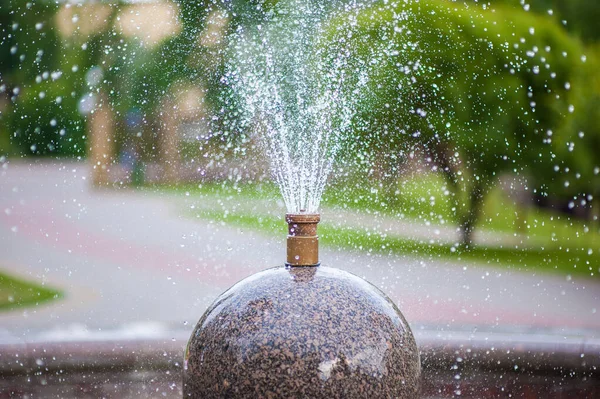 En fontän i form av en boll med inbyggda rör, från vilka vatten rinner ner över torget, stänk allt runt — Stockfoto