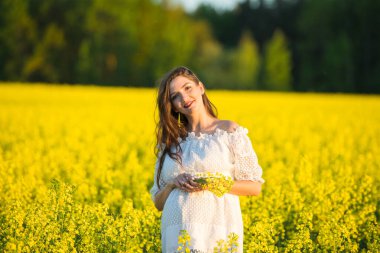 Elinde çiçek tutan hamile bir kız. Hamile bir kadının karnı. Hamilelik kavramı. Yeşil doğada arka plan bulanıklaştı. Hamile karnı kapanıyor. Bahar Parkı 'nda karnına dokunan hamile bir kadın.