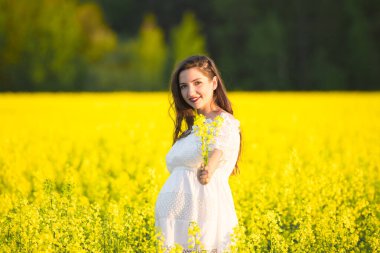 Güzel, hamile, esmer, güzel, hamile bir kadın. Sevgi ve özenle karnına dokunuyor. Kalp şeklinde..