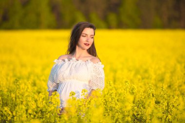 Beyaz elbiseli hamile kız. Açık havada, beyaz elbiseli güzel hamile bir kadının doğal portresi. Uzayı kopyala Resim yapmak için bir yer. Kopyalama alanı