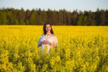 Güzel, hamile, esmer, güzel, hamile bir kadın. Sevgi ve özenle karnına dokunuyor. Kalp şeklinde..