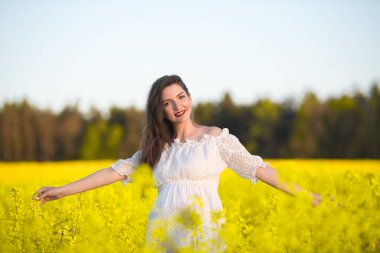 Hamileliğin kutlu olsun, kollarını açarak gülümseyen hamile bir kadın.