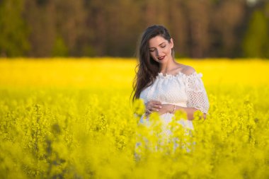 Yaz hamileliği, sıcak mevsimde. Sıcak bir yaz gününde hamile bir kadının güzel bir portresi. Hamilelik ve sezon konsepti