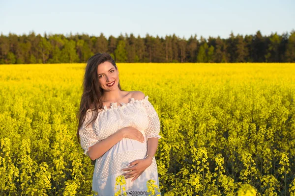 Donna felice incinta che si tocca la pancia. Ritratto di madre incinta di mezza età che si accarezza la pancia e sorride primo piano. Concetto di gravidanza sana, donna incinta bruna — Foto Stock