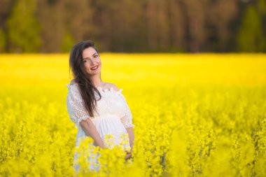 Hamile, mutlu kadın karnına dokunuyor. Hamile orta yaşlı anne portresi karnını okşuyor ve yakından gülümsüyor. Sağlıklı hamilelik kavramı, esmer hamile kadın.