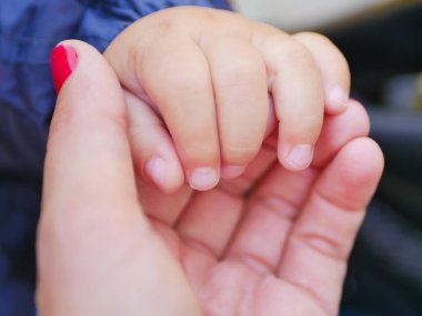 Sevgi dolu bir anne bir çocuğun elini tutar. Yeni doğmuş bir bebeğin eli