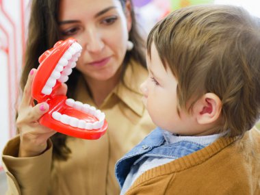İnsan çenesinin yerleşimi. Çene oyuncağı. Diş öğrencilerine çeneyi gösterme planı. Anne çocuğa çenesini gösterir..