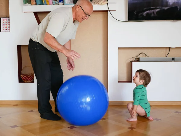 L'enfant joue avec le grand-père la balle. jouer une grosse balle bleue à la maison. Un garçon joue avec son grand-père. . — Photo