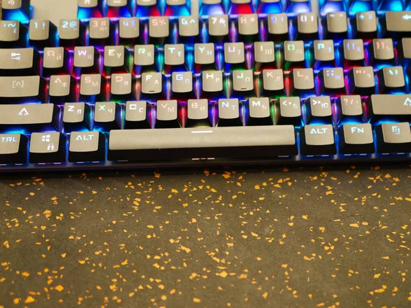 Teclado RGB. Um teclado colorido brilha com cores diferentes. deitado na mesa. Bokeh suave — Fotografia de Stock