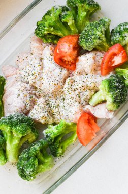 Pişirme tepsisinde çiğ hindi. Karnabahar Spomidora. Cam bir tavada çiğ hindi baharatlı tabak, üst manzara.