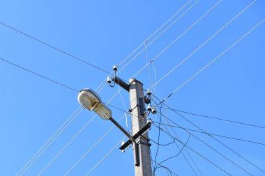 Bulutlu mavi bir gökyüzünün arka planında lamba direğiyle elektrik iletimi için kullanılan eski beton bir elektrik direği. Beni geçersiz kıl. Elektrik tedarikçisi Thod 