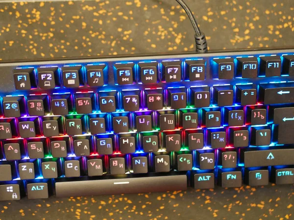 Teclado RGB. Um teclado colorido brilha com cores diferentes. deitado na mesa. Bokeh suave — Fotografia de Stock