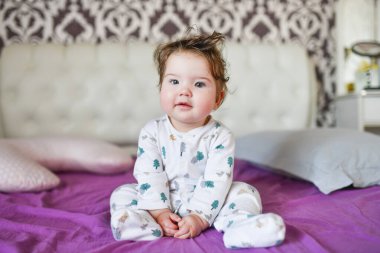 Bebek yatakta kameraya poz veriyor. Çocuk yatakta oynuyor..