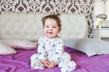 Aydınlık bir yatak odasında yeni yürümeye başlayan bir çocuk. Tatlı bir rüyadan sonra. çok renkli çarşaflar