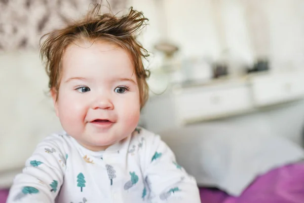 Schattige baby, van dichtbij. Portret van een kruipende baby op het bed in haar kamer — Stockfoto