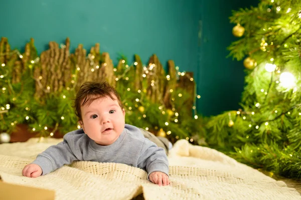 Bebê e conceito de Natal. Bebê com fundo de Natal na temporada de inverno, bebê saudável e conceito de inverno. Férias de Ano Novo. um presente debaixo da árvore . — Fotografia de Stock