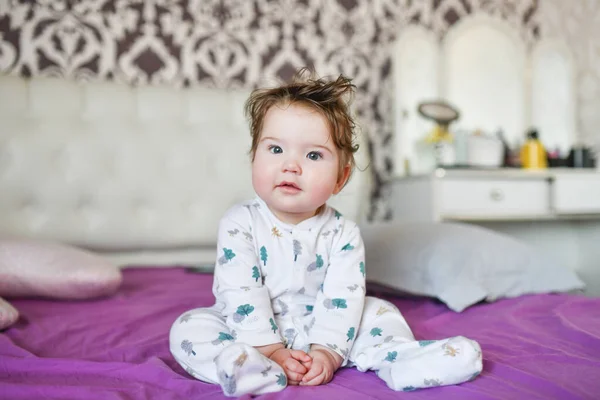 De baby zit op het bed. Leuk meisje op het bed in de slaapkamer — Stockfoto