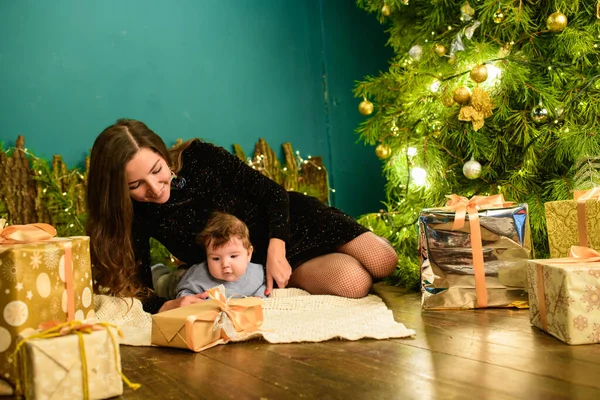 Baby with mother at Christmas. happy family mother and baby little son playing home on Christmas holidays. New Year's holidays. Toddler with mom in the festively decorated room with Christmas tree. Po