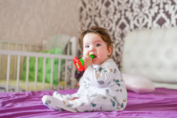 Baby knabbelt aan een speeltje. close-up portret klein schattig meisje met grote blauwe ogen met een speelgoed in haar handen, knabbelt een bijtring speelgoed — Stockfoto