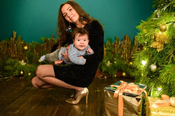 happy mom with baby in new year setting. a young woman and a seven-year-old child look at the camera in a Christmas setting. family at Christmas. Happy Mom and son at the Christmas tree