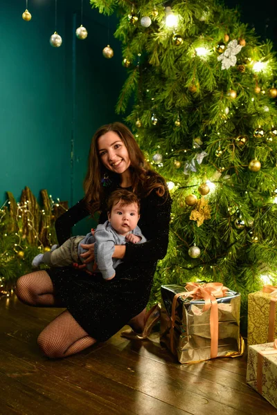 happy mom with baby in new year setting. a young woman and a seven-year-old child look at the camera in a Christmas setting. family at Christmas. Happy Mom and son at the Christmas tree