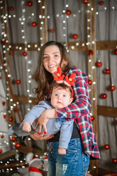 Noel ağacında anne ve bebek kucaklaması. Mutlu bebek ve annesi çerçeveye bakıyorlar. Noel'de oğluyla birlikte anne kucaklıyor. ve eğlenin. yeni yıl için yenidoğan bebek. — Stok fotoğraf