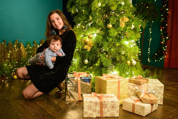 Glückliche Mutter mit Baby im neuen Jahr Einstellung. Eine junge Frau und ein siebenjähriges Kind blicken weihnachtlich in die Kamera. Familie zu Weihnachten. glückliche Mutter und Sohn am Weihnachtsbaum — Stockfoto