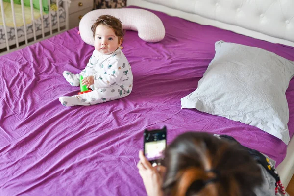 Máma fotí dítě na telefonu. Zavři ten telefon. Máma fotografoval její malý syn-dívka pomocí zařízení-orientované smartphone — Stock fotografie