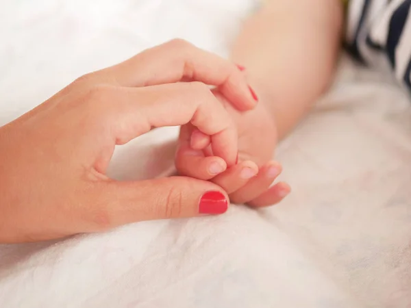 Máma drží za ruku novorozence. Detailní záběr. Místo na psaní. Umísťuji text. rozostřující. Dětská ruka drží prst na mamince. — Stock fotografie