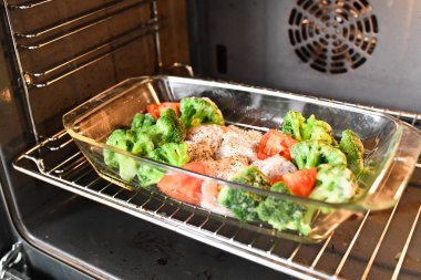 Pişirme tepsisinde çiğ hindi. Karnabahar Spomidora. Cam bir tavada çiğ hindi baharatlı tabak, üst manzara.