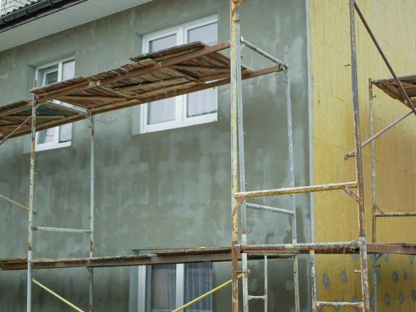 external warming of a private house. Outdoor work. There are rails for workers. Warming of the apartment house. External repair work on the building, insulation and cladding of the facade of the house
