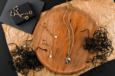 Kolyeli altın küpeler. Yakın plan. Tahta bir tezgahta yatıyordu. Yukarıdan bak. Mücevher ve mücevher kavramı. Kadınlar için hediyeler. Alışveriş. El işi.