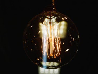 Yanardöner lamba. Klasik stilize edilmiş tungsten lamba. Seçici odaklı, karanlık ve yakın plan bir fotoğrafta parlıyor. Yakın plan. Karanlık arka plan. Odaklanma arkaplanı.