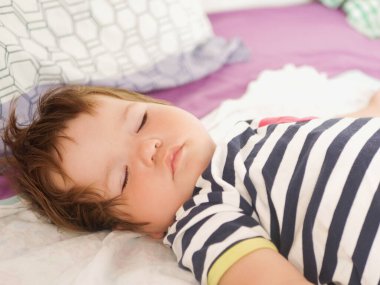 Ebeveyn yatağında uyuyan bebek. 0-1 yaşında bir bebek. Ebeveyn yatağında yeni doğmuş bir bebeğin portresi. Bebeğin gündüz uykusu. Çocukların tasasız hayatı. İyi uykular bebeğim..